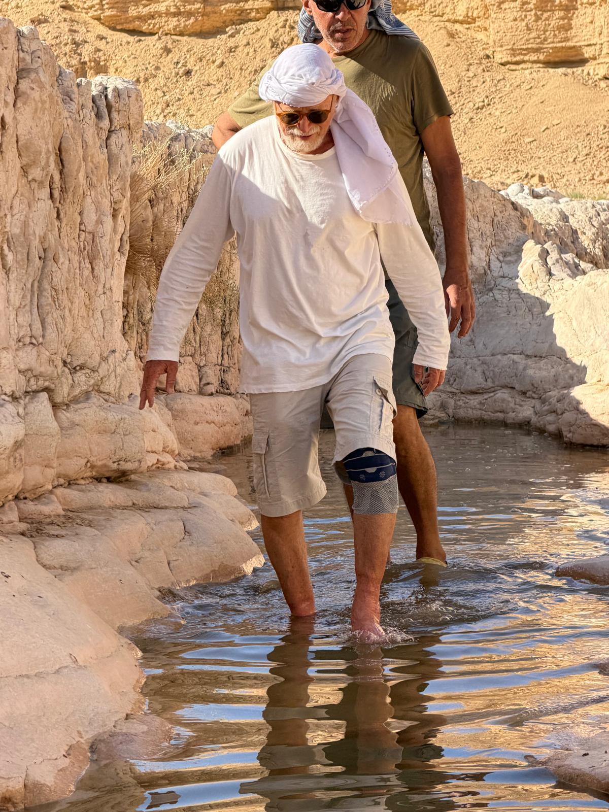 מטיילים הולכים במים רדודים בין סלעים לבנים