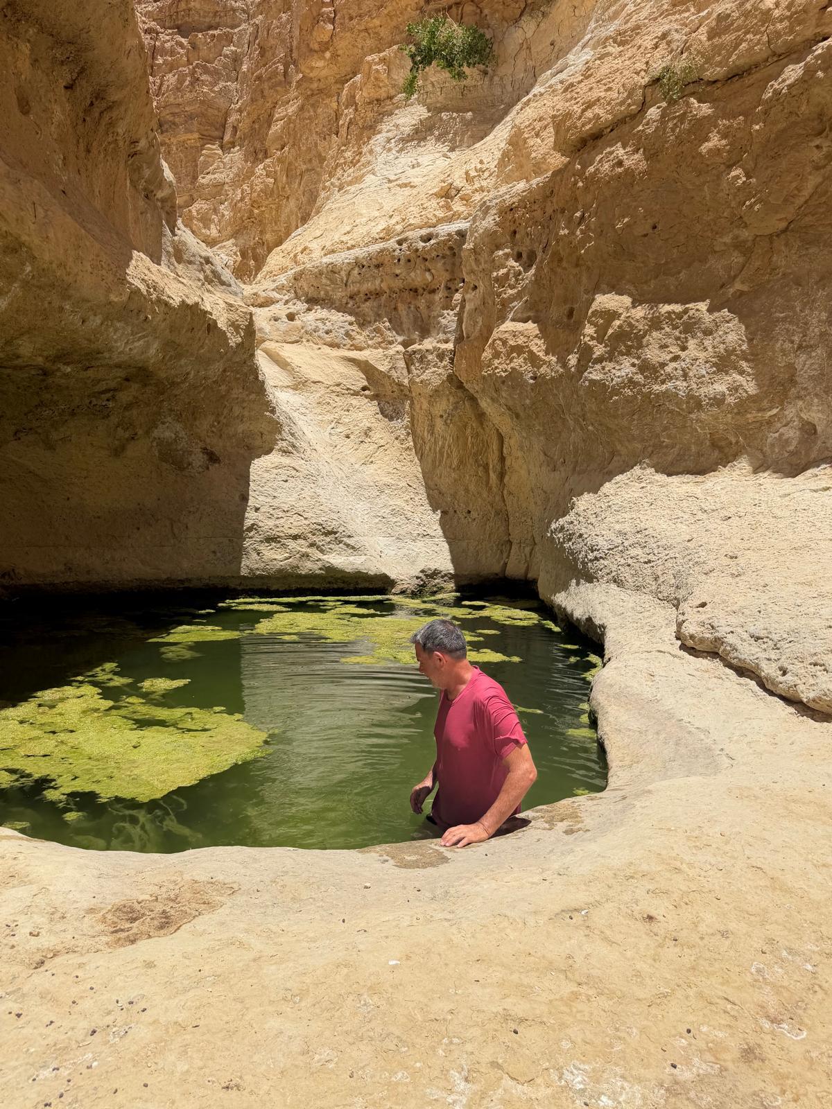 מטייל במים של גב ירקרק בתוך ערוץ סלעי